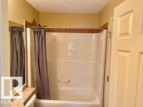 White tub and shower combination with brown tile surround - 1 5281 Terwillegar Boulevard, Edmonton, AB 