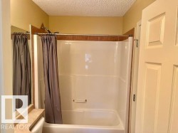 White tub and shower combination with brown tile surround - 