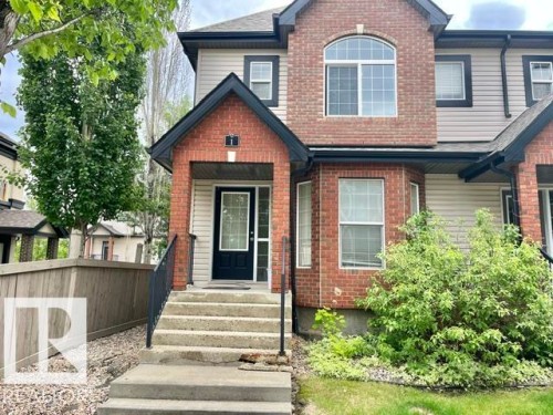 Brick and siding exterior featuring a prominent arched window and a bay window - 1 5281 Terwillegar Boulevard, Edmonton, AB 