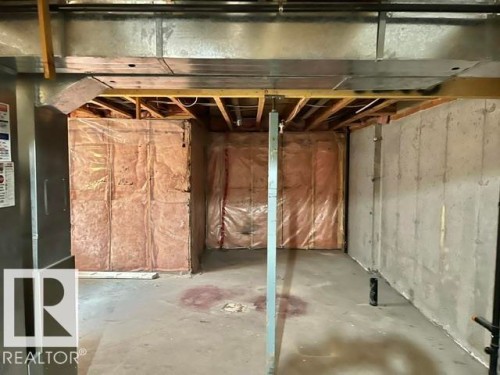 Unfinished basement space featuring exposed concrete walls and flooring, structural support beams, and visible insulation - 1 5281 Terwillegar Boulevard, Edmonton, AB 