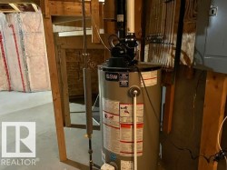 GSW water heater unit with associated piping, electrical conduit, and exposed wood framing - 