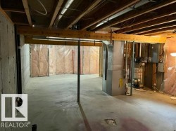 Unfinished basement featuring exposed wood joists, concrete flooring, and insulated perimeter walls - 