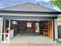 Detached garage featuring a shingled roof, exterior siding, built-in shelving, concrete flooring, and a workbench area - 1 5281 Terwillegar Boulevard, Edmonton, AB 