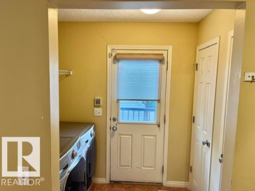 Utility area featuring a rear exterior door with integrated window, a built-in pantry, and overhead wire shelving - 1 5281 Terwillegar Boulevard, Edmonton, AB 