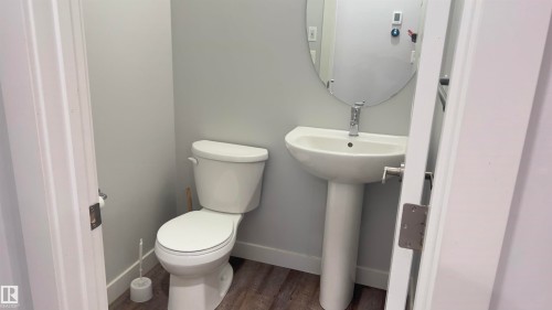 Pedestal sink with chrome faucet, oval mirror, and wood-finish flooring - 90 804 Welsh Drive, Edmonton, AB 
