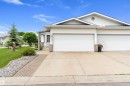 Front exterior featuring a multi-car garage, concrete driveway, and landscaped grounds - 15577 59A Street, Edmonton, AB 