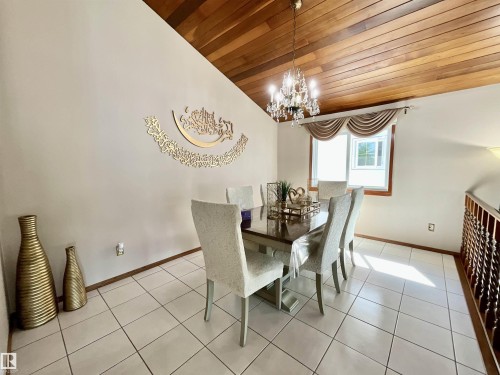 Dining area featuring a vaulted wood-paneled ceiling, chandelier lighting, and large window with valance - 11031 166 Avenue, Edmonton, AB 