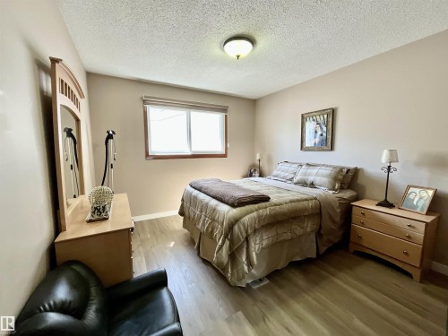 Bright room featuring wood-finish flooring, neutral wall tones, and a textured ceiling - 11031 166 Avenue, Edmonton, AB 