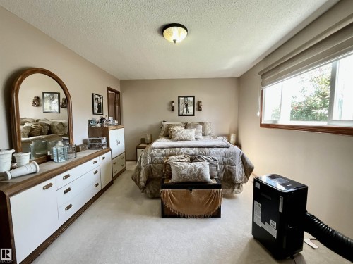 Carpeted room with neutral-toned walls, featuring a wide window with a neutral roller shade and wood trim - 11031 166 Avenue, Edmonton, AB 
