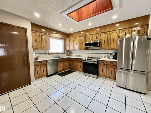 Kitchen featuring extensive wood cabinetry, white tile flooring, and a skylight - 11031 166 Avenue, Edmonton, AB 