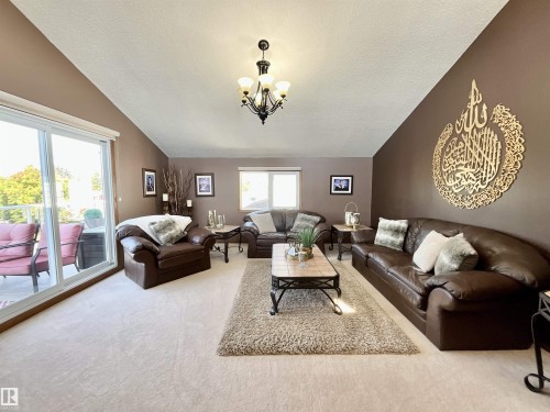 Spacious living area featuring vaulted ceilings, light-toned carpeting, and a glass sliding door opening to an outdoor patio - 11031 166 Avenue, Edmonton, AB 