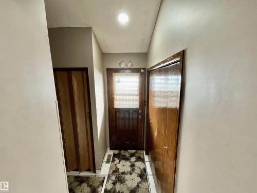 Entryway featuring a dark wood door with integrated blinds, a flush-mount ceiling light, and tile flooring - 11031 166 Avenue, Edmonton, AB 