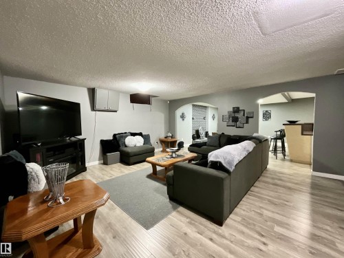 Spacious living area featuring wood-finish flooring, light gray wall tones, and arched doorways - 11031 166 Avenue, Edmonton, AB 