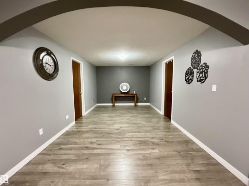 Archway entry opening into a hallway with wood-finish flooring, light gray walls, and white baseboards - 11031 166 Avenue, Edmonton, AB 