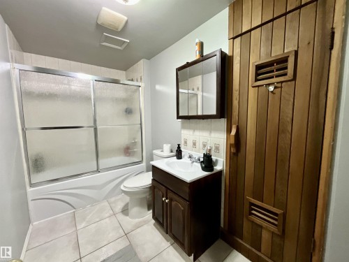 Full bathroom featuring a white vanity with integrated sink, a medicine cabinet, and a shower-over-tub with sliding glass doors - 11031 166 Avenue, Edmonton, AB 