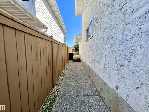 Exposed aggregate walkway with a natural wood fence and stucco exterior - 11031 166 Avenue, Edmonton, AB 