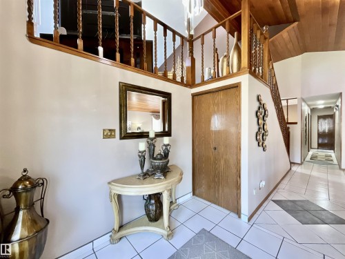 Foyer featuring a grand staircase with carved wood balusters and a wood-paneled ceiling - 11031 166 Avenue, Edmonton, AB 