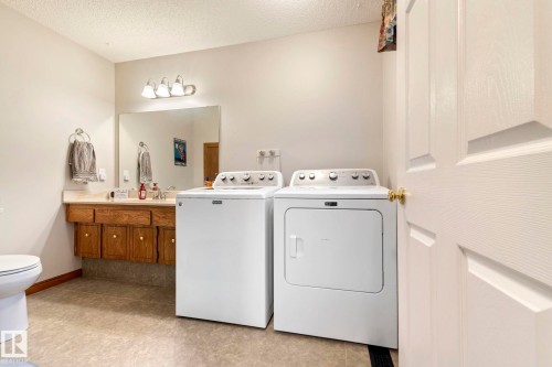 Utility area featuring a wall-mounted vanity with a single sink and wood-finish cabinetry - 9940 83 St, Fort Saskatchewan, AB 