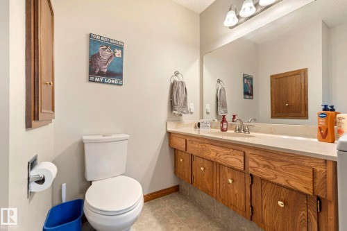 Bathroom featuring a wide vanity with wood cabinetry, a large mirror, and a built-in toilet - 9940 83 St, Fort Saskatchewan, AB 