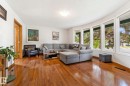 Expansive living area featuring wood-finish flooring, a curved wall with multiple large windows, and a recessed ceiling light fixture - 9940 83 St, Fort Saskatchewan, AB 
