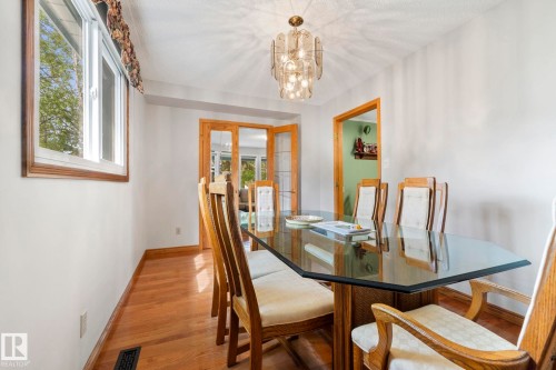 Dining area featuring wood-finish flooring, a contemporary chandelier, and white wall finishes - 9940 83 St, Fort Saskatchewan, AB 