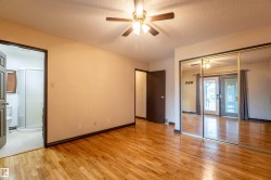 Spacious room with wood-finish flooring, a ceiling fan, and mirrored closet doors - 