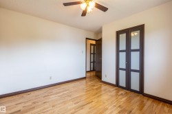 Room featuring wood-finish flooring, white walls, and dark wood-frame closet doors with frosted glass panels - 