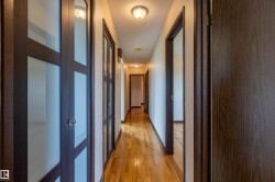 Hallway featuring wood-finish flooring, warm white wall finishes, and ceiling-mounted flush light fixtures - 
