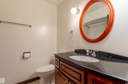 Bathroom featuring a wood-finish vanity with an integrated sink and dark countertop, an oval wood-frame mirror, and a wall-mounted light fixture - 