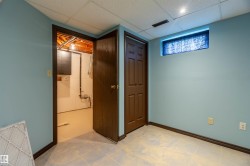 Basement room with light blue painted walls, drop ceiling, and light-toned floor tiles - 