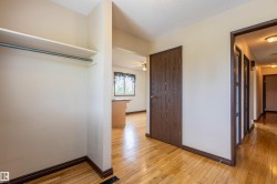 Hallway featuring wood-finish flooring, a closet with shelving and a hanging rod, a dark wood-finish door, and recessed lighting - 