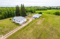 White single-story residence with a gray shingled roof, a long gravel driveway, and a detached white garage - 