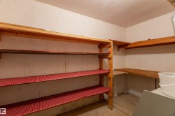 Utility room featuring extensive built-in wooden shelving, a corner work surface, and a light-colored ceiling - 