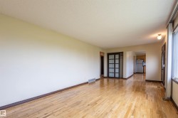 Expansive interior space featuring wood-finish flooring, a neutral wall palette, and white trim - 