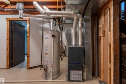 Dedicated utility area featuring a water heater, furnace, and exposed ceiling joists - 
