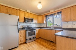 Kitchen featuring wood-finish cabinetry, dark countertops, a stainless steel electric range, and a stainless steel built-in microwave - 