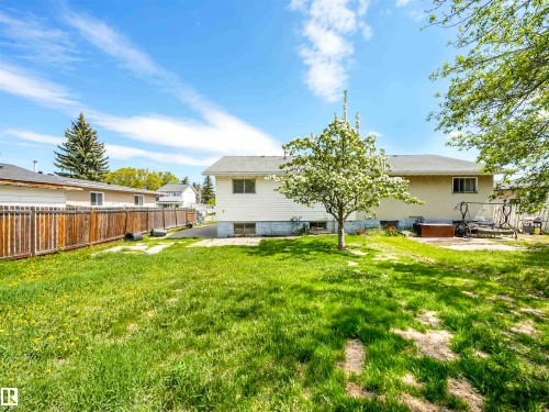 Expansive backyard featuring a mature flowering tree, concrete paver pathway, wood privacy fencing, and a stucco exterior - 13114 30 Street, Edmonton, AB - Outdoor