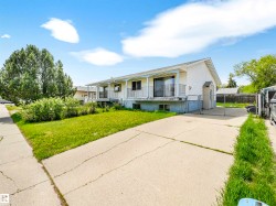White siding exterior with a covered front balcony, multiple sliding glass doors, a concrete driveway, and a fenced side yard - 