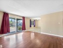 Spacious living area featuring wood-finish flooring, light tan wall paint, and white trim - 13114 30 Street, Edmonton, AB  - Indoor Photo Showing Other Room 