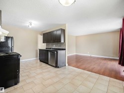 Kitchen area with light-toned tiled flooring, dark wood-finish cabinetry, and a stainless steel dishwasher - 