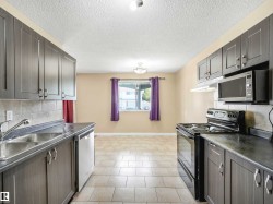 Kitchen with dark cabinetry, light countertops, and tile flooring - 