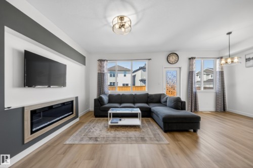 Open-concept living area featuring light wood-finish flooring and a built-in electric fireplace with a light wood-tone surround - 1684 12 Street, Edmonton, AB 