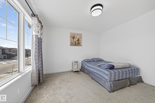 Room featuring a large multi-pane window, wall-to-wall carpeting, white painted walls, and a contemporary flush-mount ceiling light - 1684 12 Street, Edmonton, AB 