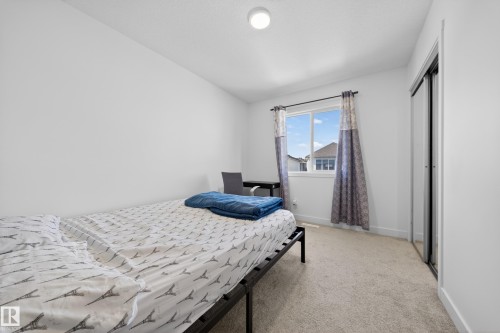 Carpeted room with a double window, overhead flush mount lighting, and a sliding door closet with mirrored panels - 1684 12 Street, Edmonton, AB 