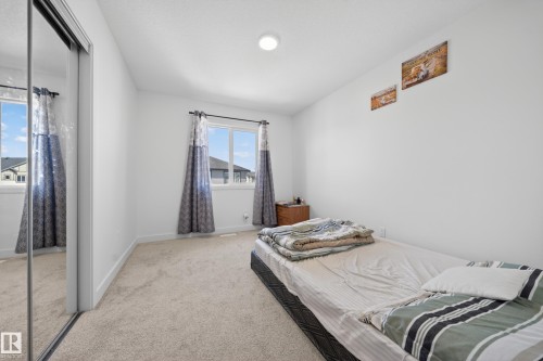 Carpeted room featuring a double-paned window, mirrored sliding closet doors, and recessed ceiling lighting - 1684 12 Street, Edmonton, AB 