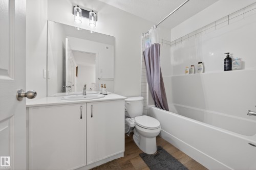 Bathroom featuring a white vanity with an integrated sink, polished chrome faucet, and a large wall-mounted mirror - 1684 12 Street, Edmonton, AB 
