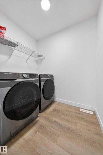 Laundry area featuring wood-finish flooring, white baseboards, a ceiling-mounted light fixture, and wire shelving - 1684 12 Street, Edmonton, AB 
