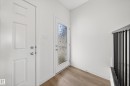 Entryway featuring a white paneled door, a second door with a decorative glass insert, wood-finish flooring, and a staircase with black metal balusters - 1684 12 Street, Edmonton, AB 