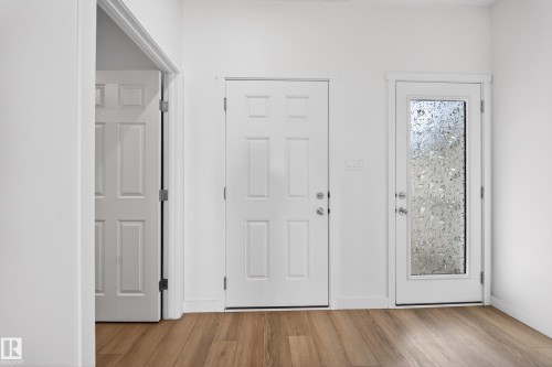 Entryway featuring wood-finish flooring, two white paneled doors, and a full-light door with frosted glass - 1684 12 Street, Edmonton, AB 