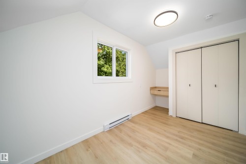 Light-filled room featuring wood-finish flooring, a white window frame, and a built-in wooden desk - 10866 92 Street, Edmonton, AB 